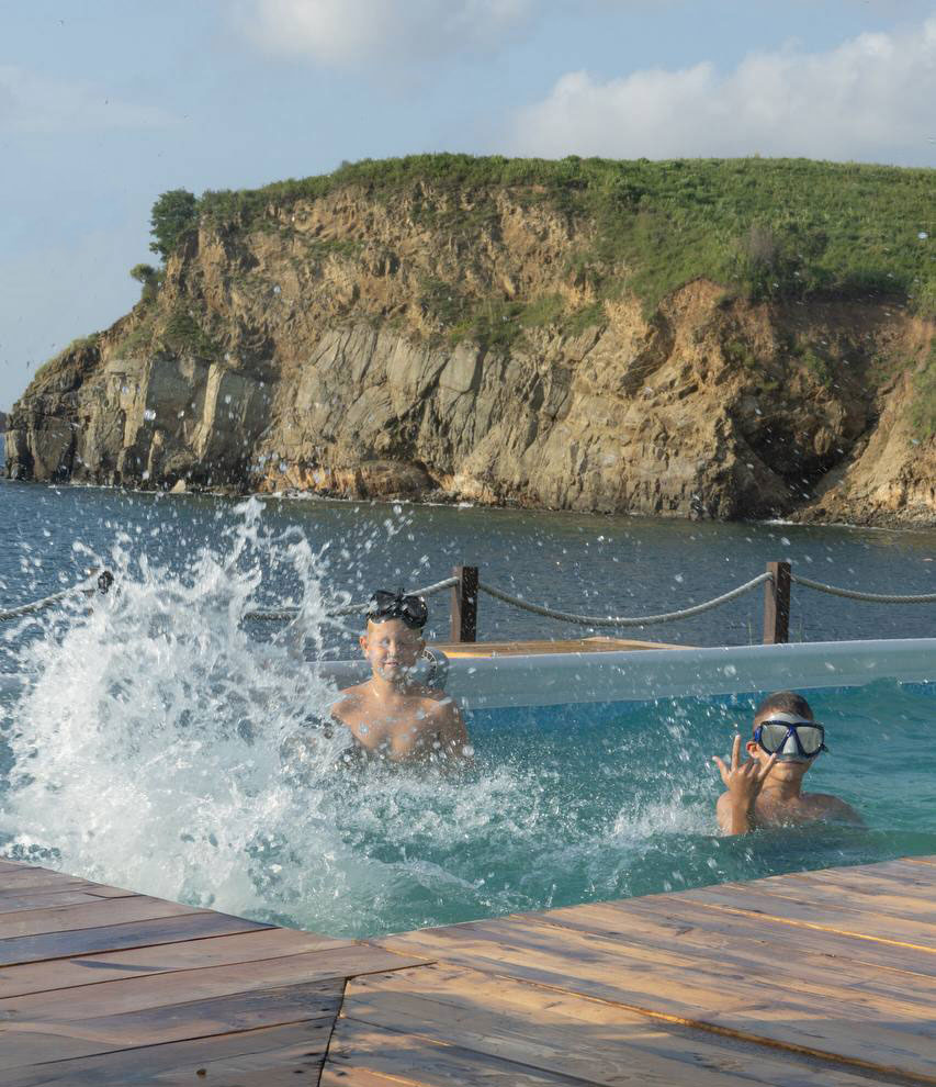 Дети в бассейне на фоне скал